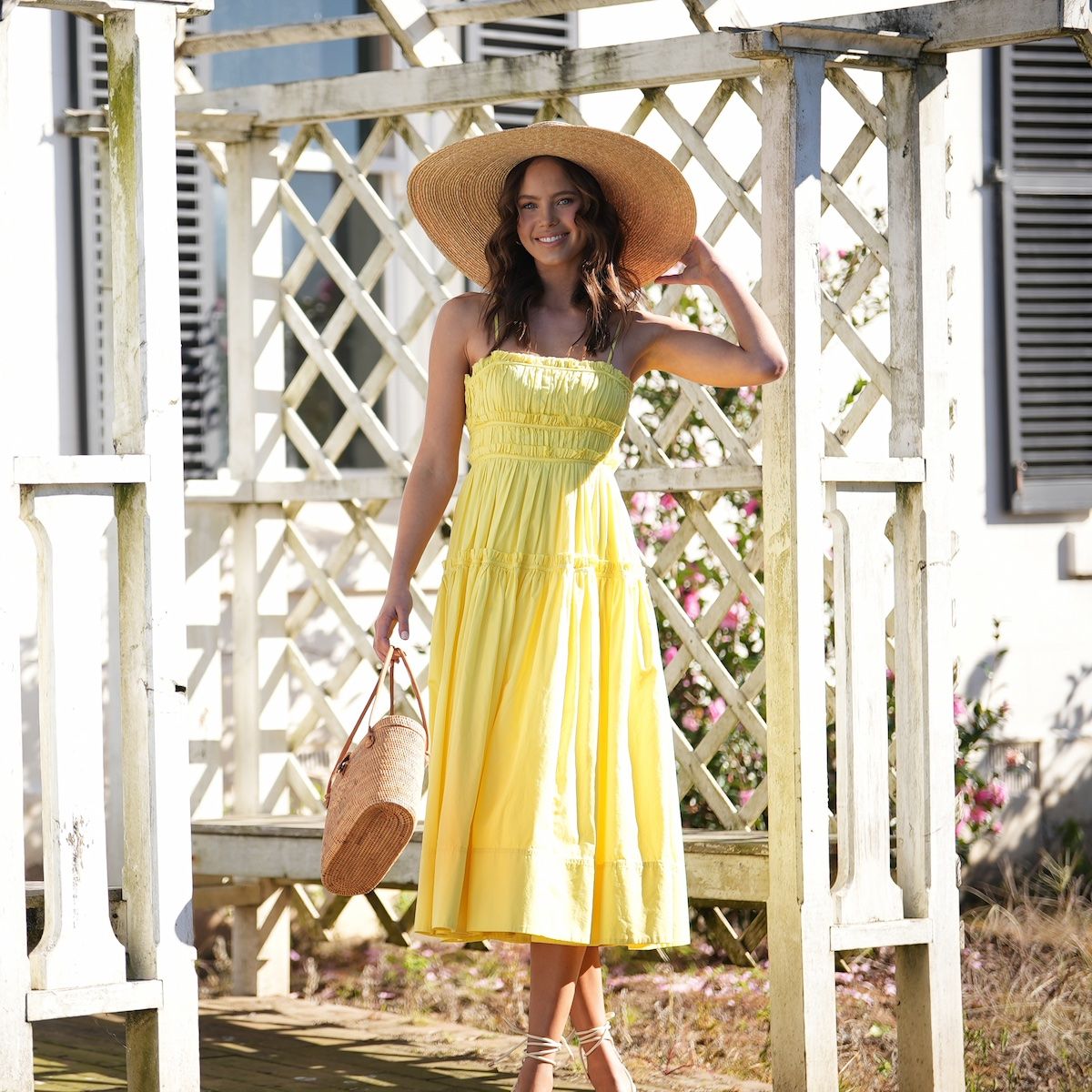 Model wearing yellow dress with straw hat