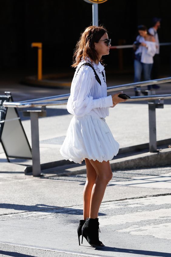 Christine Centenera wears a white mini dress with black heeled ankle boots.